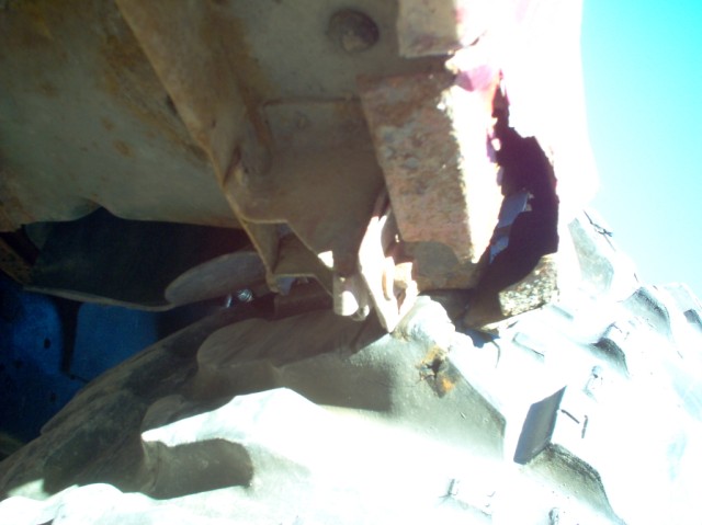 rusted metal frame bracketry above a large tire