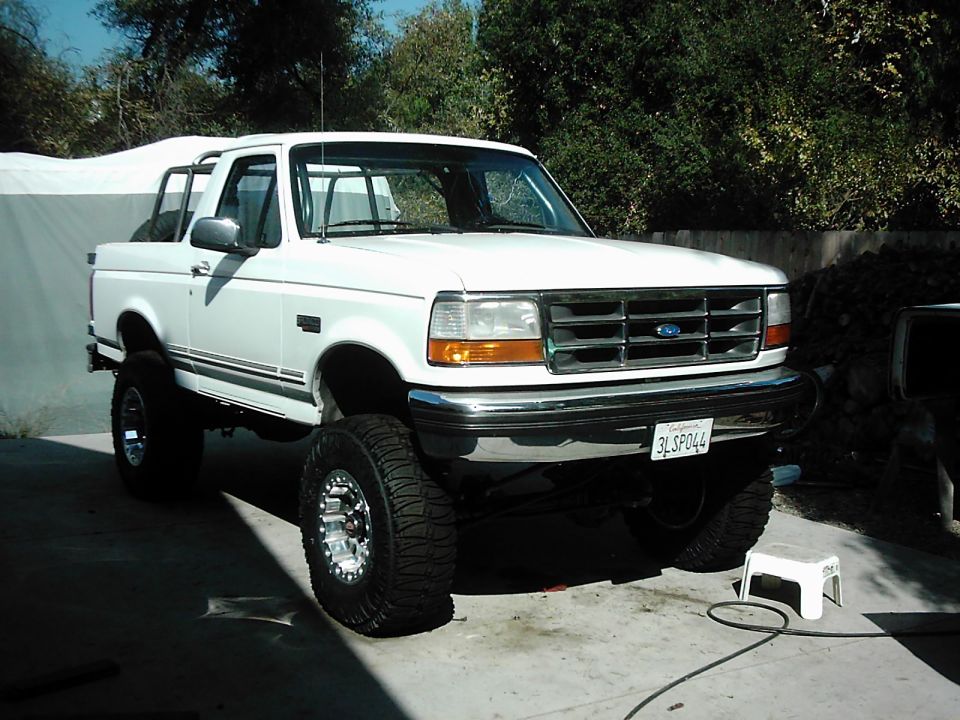 White lifted Ford F-150 pickup truck with chrome wheels and off-road tires