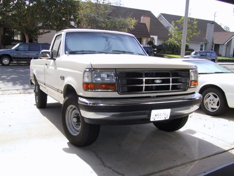 2000 Ford Crown Victoria - A white Ford F-Series truck is parked in a driveway with another car visible to the right.