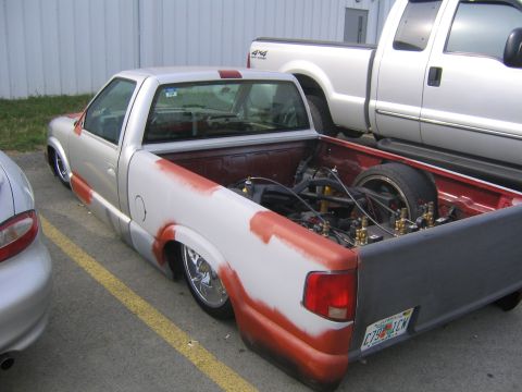1978 Ford Bronco - A modified pickup truck sits low to the ground, revealing its custom suspension and engine parts in the bed.