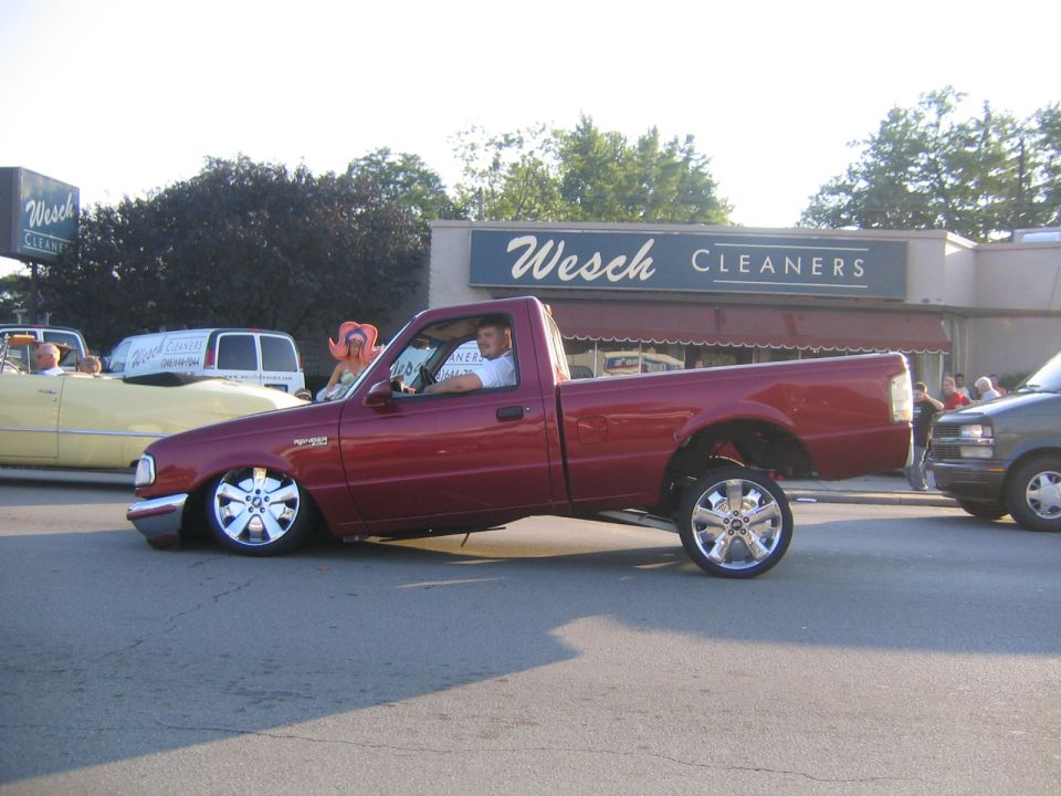 Red pickup truck with chrome wheels and extremely low suspension, seen from the side