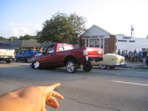 1978 Ford Bronco - Red pickup truck with custom lowered suspension and chrome wheels is parked on the street.