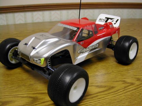 1994 Ford Bronco - A red and silver remote control car sits on a wooden table, displaying 'Team Associated' branding.