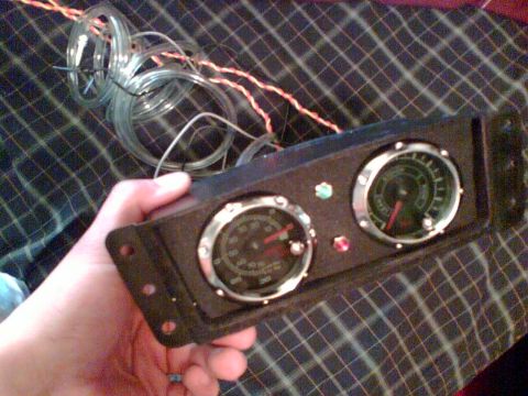 1997 Ford Probe - A hand holds a custom gauge cluster with two gauges and associated wiring and tubing.