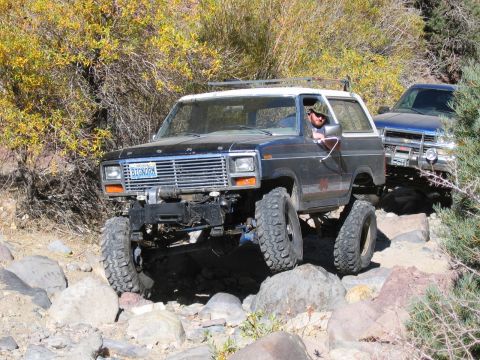 1986 Ford Bronco - A modified Ford Bronco navigates a rocky trail, with another vehicle following closely behind.