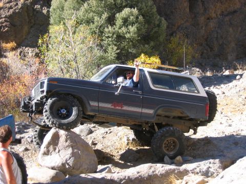1986 Ford Bronco - Ford Bronco tackling a challenging off-road trail with large rocks.