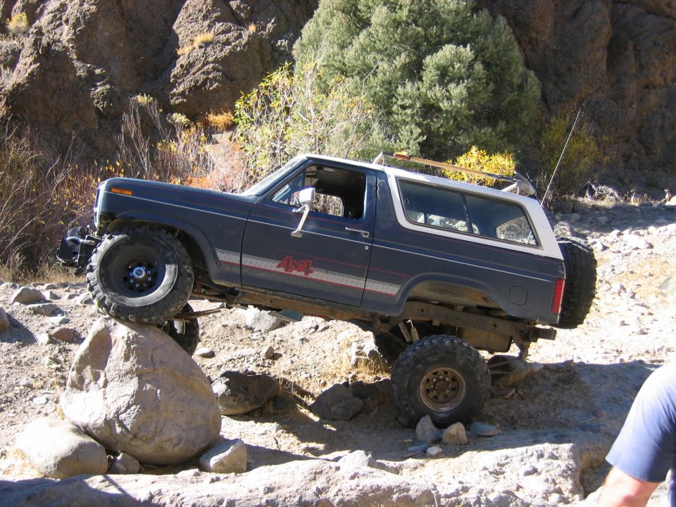 1986 Ford Bronco on a rocky trail, front tire on a large boulder