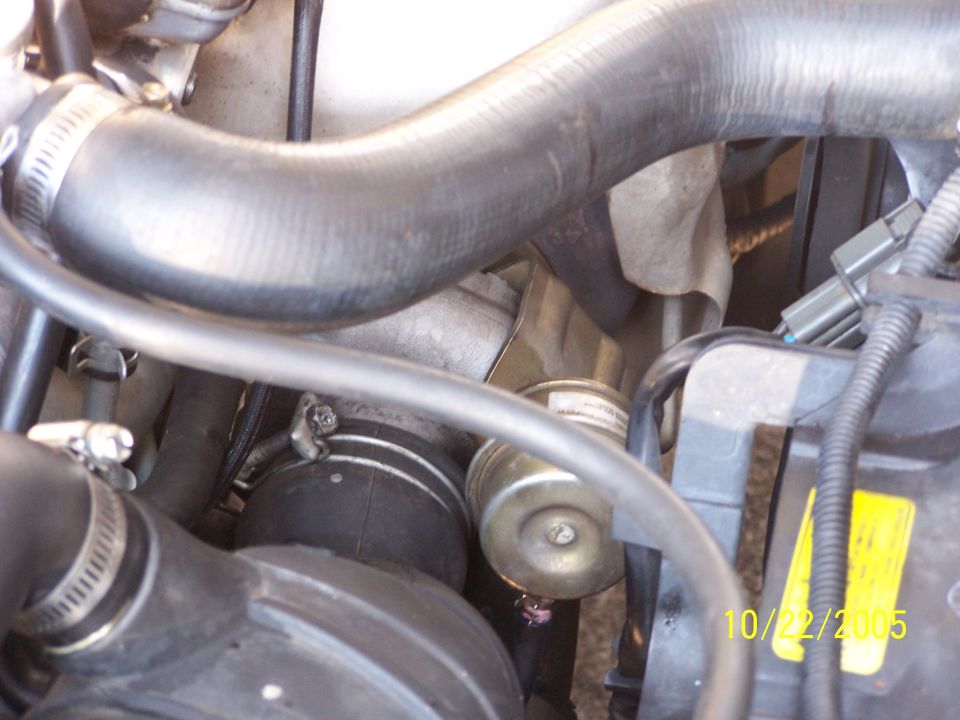 Engine bay with hoses, a turbocharger, and a yellow sticker. Date stamp reads 10/22/2005