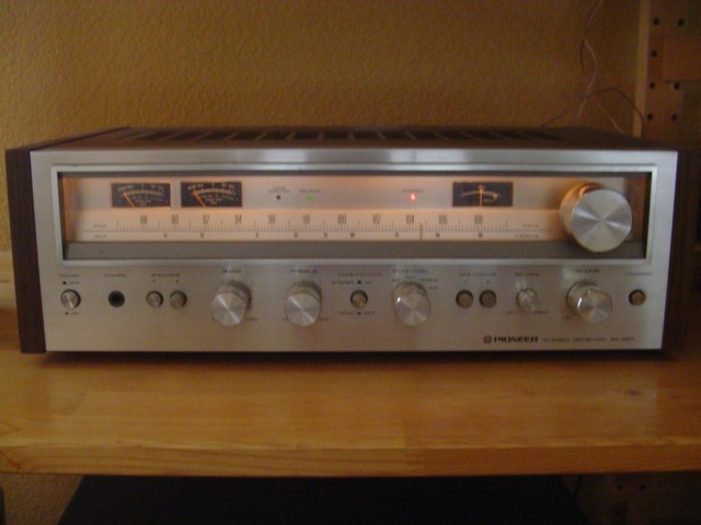 Vintage Pioneer wood-cased stereo receiver with lit tuning dial on a wood shelf