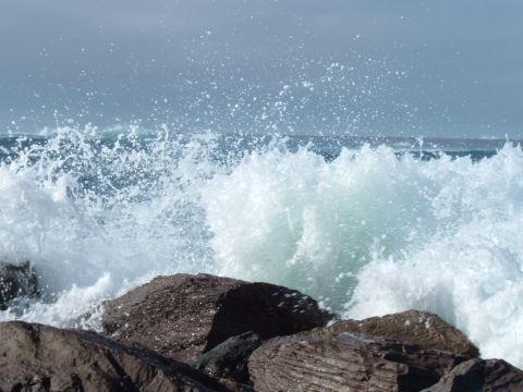 2000 Ford F-250 - Waves surge and break over rocks near the shore on a cloudy day.