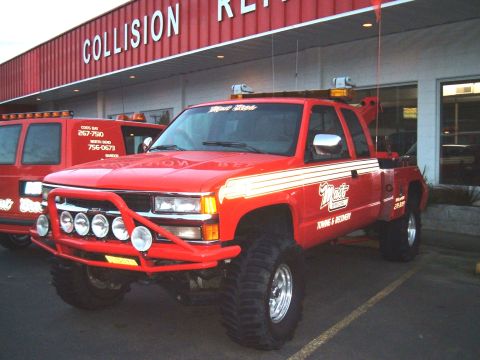 2000 Ford F-250 - A red tow truck with 'Mait Towing & Recovery' decals is parked outside a collision repair business.