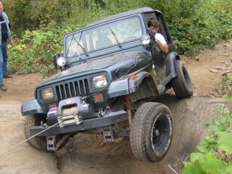 1990 Ford Bronco - A green Jeep Wrangler navigates a rocky off-road trail with a winch attached to the front bumper.