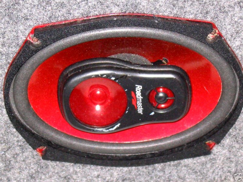 Roadmaster 6x9 three-way car speaker with red cone mounted in gray carpeted panel