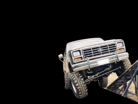 1986 Ford Bronco - A lifted Ford Bronco is shown on a ramp, demonstrating its off-road capabilities.