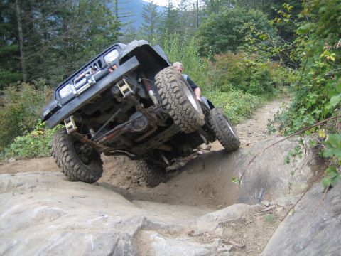 1990 Ford Bronco - An off-road vehicle navigates a challenging rocky terrain on a dirt path.