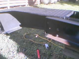 1986 Ford Bronco - Close-up of a black winch plate bumper installed on a vehicle, with a yellow cable lying on the grass nearby.