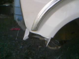 1986 Ford Bronco - Detail of a vehicle's fender and wheel well, showing damage and some chrome trim.