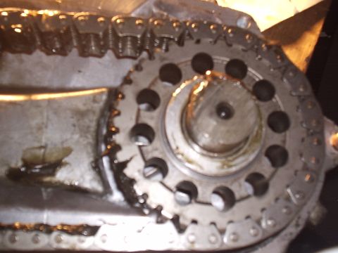 1985 Ford Bronco - Close-up looking into an opened transfer case, showing the wide drive chain wrapped around a lightened sprocket with a ring of drilled hole…