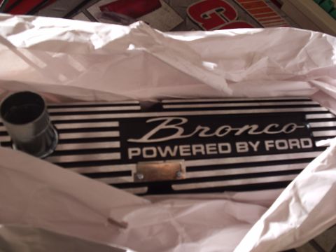 1985 Ford Bronco - A new finned aluminum valve cover sitting in white tissue paper inside its box, its black-and-polished face reading "Bronco: POWERED BY FOR…
