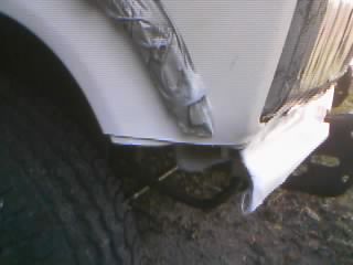 1986 Ford Bronco - Close-up view of a white vehicle's front fender and bumper area, showing a winch plate installation.