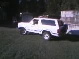 1986 Ford Bronco - A white 1986 Ford Bronco is parked on a grassy area, seen from the front three-quarter angle.