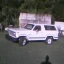 1986 Ford Bronco - A white Ford Bronco from the 1980s is parked outdoors on a grassy area with trees in the background.