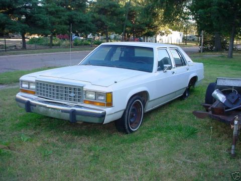 1991 Ford LTD Crown Victoria - This white sedan has a distinctive grille and bumper, suggesting an earlier model year than claimed.