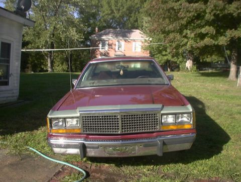 1991 Ford LTD Crown Victoria - Maroon sedan with a prominent chrome grille and rectangular headlights sits in a yard.