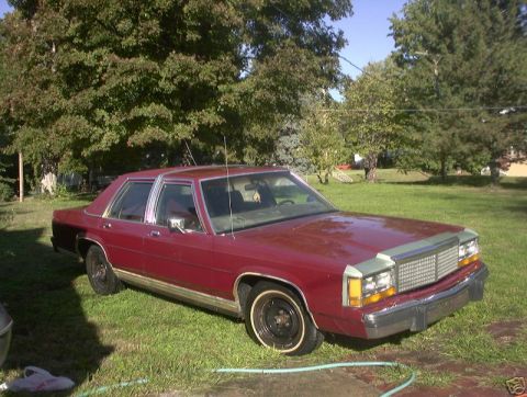 1991 Ford LTD Crown Victoria - This sedan has a distinctive grille and headlight design, suggesting an older model year.