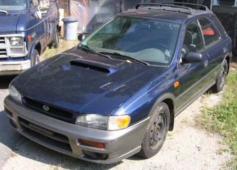 1997 Subaru Impreza - A blue 1997 Subaru Impreza wagon is parked outdoors next to a blue van.