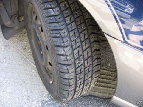 1997 Subaru Impreza - A close-up view of a vehicle's tire and fender area, revealing a portion of the body with a decorative stripe.