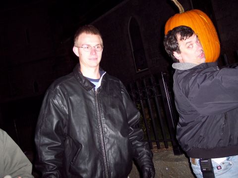 2001 Ford Crown Victoria - Two men are seen outdoors at night, one with a large pumpkin balanced on his head.