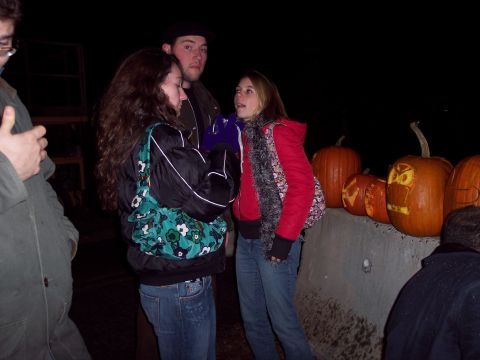 2001 Ford Crown Victoria - A group of people stand near carved pumpkins on a concrete ledge at night.