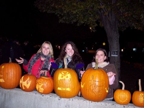 2001 Ford Crown Victoria - Women pose with carved pumpkins during a nighttime event.