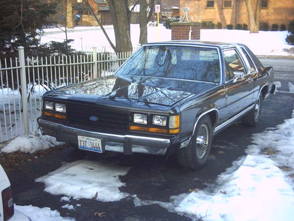 Black sedan with chrome trim parked on a snowy driveway