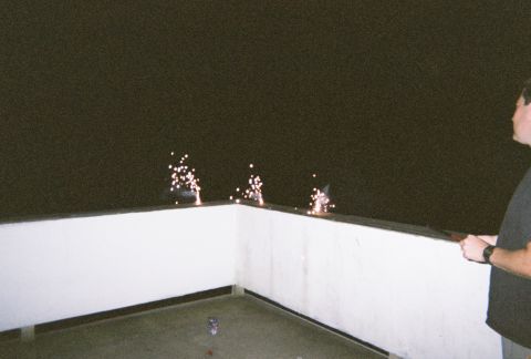 1990 Ford Bronco - Fireworks are set off on a railing at night, with a person observing.