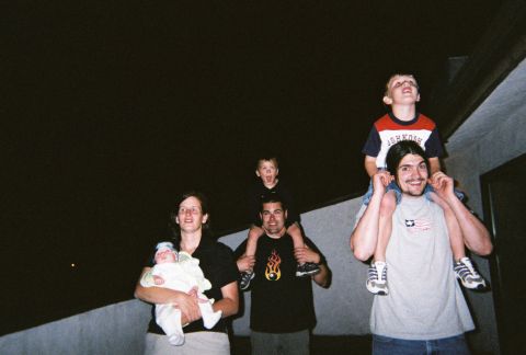 1990 Ford Bronco - A group of people, some with children on their shoulders, are gathered together looking upwards.
