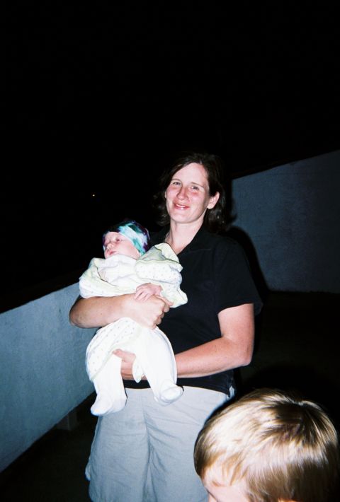 1990 Ford Bronco - A woman holds a baby while standing outdoors at night, with another child in the foreground.