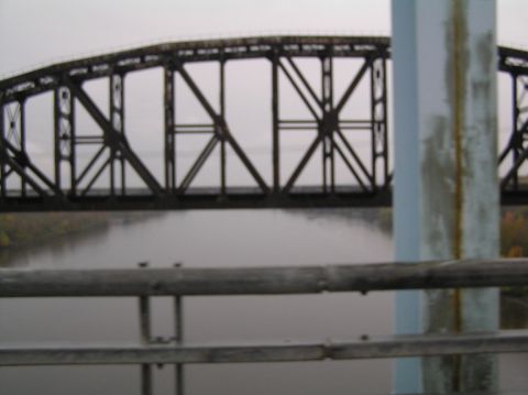 1997 Subaru Impreza - A metal railroad bridge spans a misty river, with railings in the foreground.