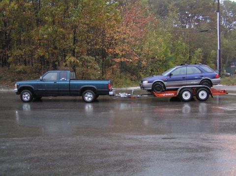 1997 Subaru Impreza - Teal pickup truck tows a blue 1997 Subaru Impreza wagon on a U-Haul trailer.