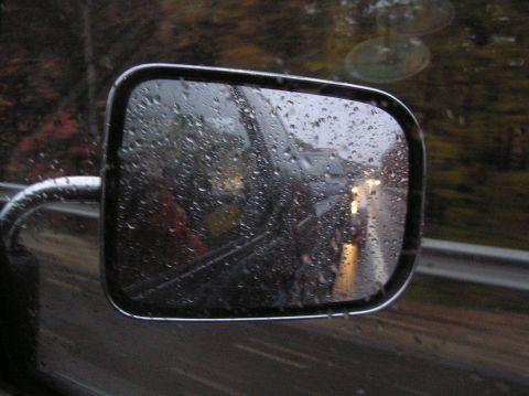 1997 Subaru Impreza - Reflection in a side view mirror shows traffic on a wet road during a rain shower.