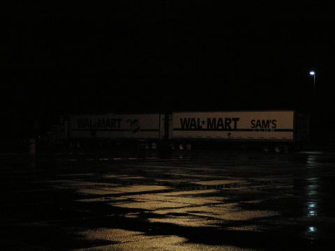 1997 Subaru Impreza - Two semi-trailers are parked in a wet lot at night, illuminated by a single streetlamp.