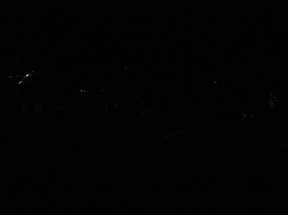 Nearly black night photo of a dimly lit parking lot with a faint trailer outline