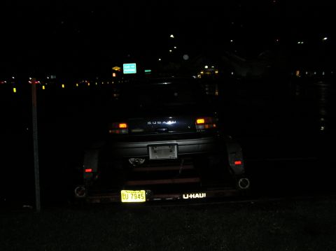 1997 Subaru Impreza - A dark 1997 Subaru Impreza sedan is loaded onto a U-Haul trailer at night.