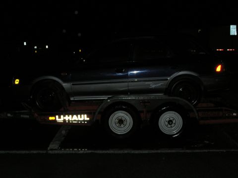 1997 Subaru Impreza - Car being transported on a U-Haul trailer at night.
