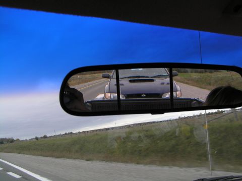 1997 Subaru Impreza - A dark blue 1997 Subaru Impreza WRX is seen following behind in the rearview mirror on a highway.