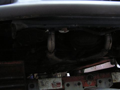1997 Subaru Impreza - Underbody view of a vehicle, focusing on the exhaust system and support structures. Text is visible on a label.