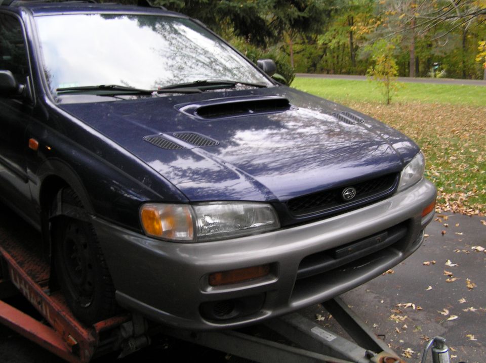 Dark blue Subaru Impreza wagon on a flatbed tow truck, front-left view