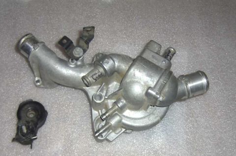 1997 Ford Taurus - Thermostat housing assembly with hoses and a separate sensor part, likely for a vehicle engine.