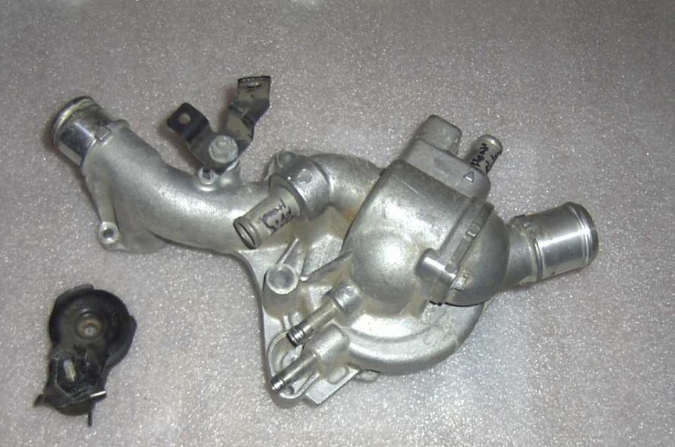 Aluminum thermostat housing with attached hoses and a separate black sensor component